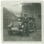 1920s. Germany. Young man sitting on the car in front of the shed. Black and white original paper image, old photo. (2792474)