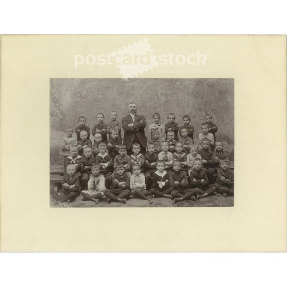Class photo with charismatic teacher. The people in the photo and the photographer are unknown. Original old photo. Black and white, laminated photo, original paper photo. (2792813)