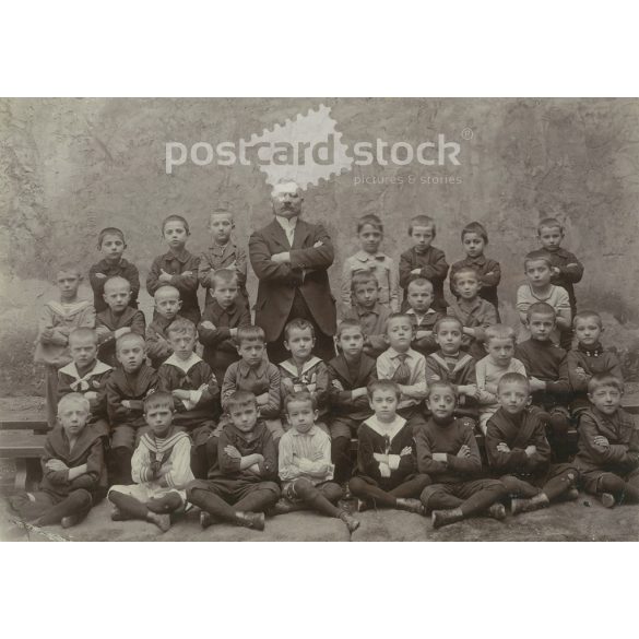 Class photo with charismatic teacher. The people in the photo and the photographer are unknown. Original old photo. Black and white, laminated photo, original paper photo. (2792813)