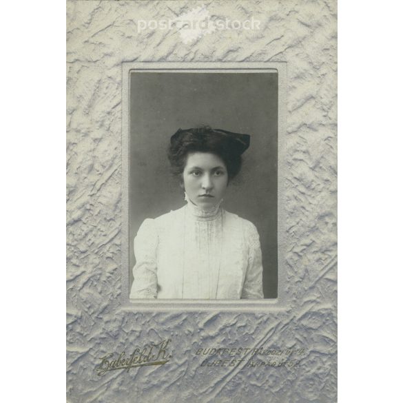 Early 1920s. Young woman in white, with a bow. The picture was taken in the photo studio of Károly Haberfeld. Black and white, laminated old photo, original paper image. (2793608)
