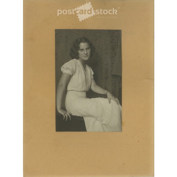 1968 – Young woman in white, studio shot. The person in the photo and the photographer are unknown. Original old photo. Black and white, laminated photo, original paper image. (2793645)