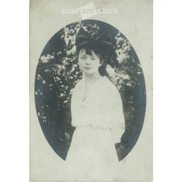 Photo of a young girl with a bow. The person in the photo and the photographer are unknown. Original old photo. Black and white photo, original paper image. (2793892)